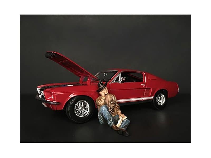 Classic Red Car Model with Open Hood and Figurine Detailed miniature red vintage car with open hood and a sitting figurine of a man in casual attire.